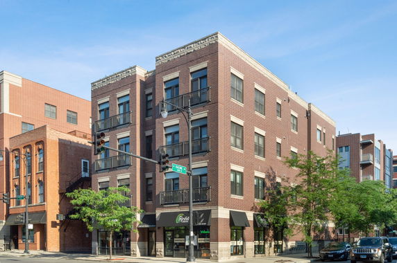 Front view of a brick multi-story building with street-level businesses.