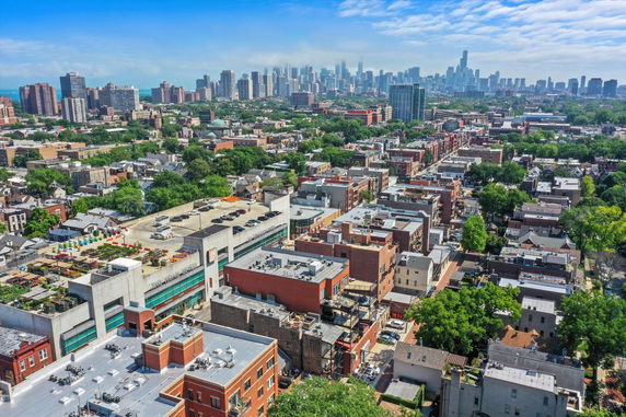 Aerial panoramic view of a city with various buildings and a skyline in the distance.