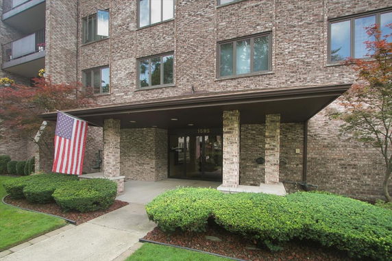 Front view of a brick building with a covered entrance and an American flag displayed.