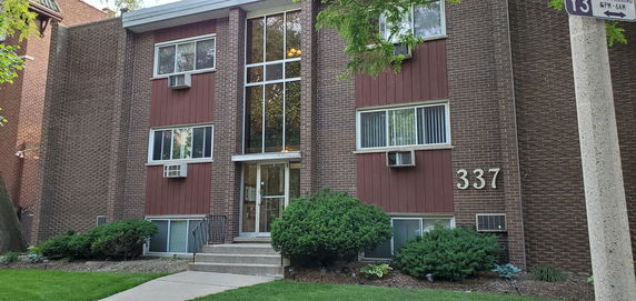 Front view of a multi-story brick apartment building with large windows.