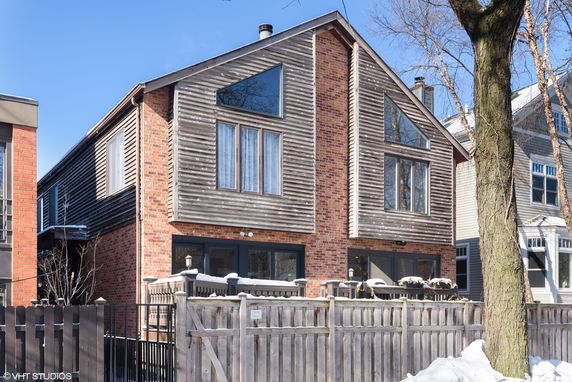 Front view of a two-story brick and wood house with gabled roof.