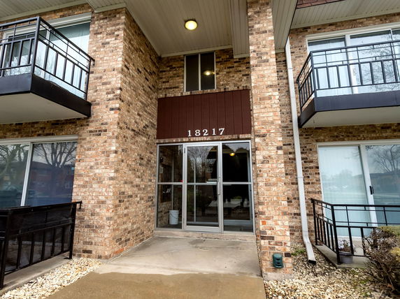 Front view of a brick building with glass doors and balconies.