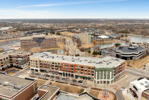 Aerial view of a commercial building complex with surrounding roads and natural landscape.