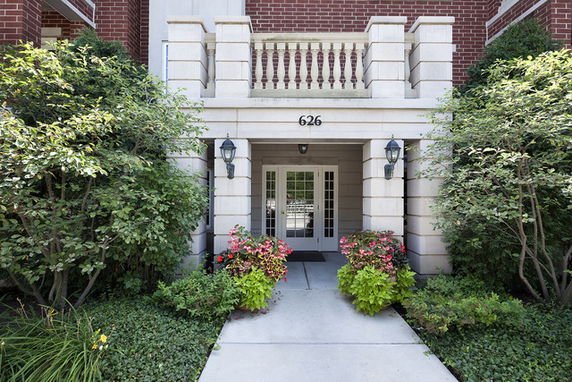 Front view of a building entrance with brick walls and a balcony above.