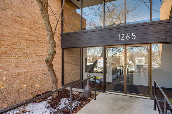 Front view of a building entrance with glass doors and brick walls.