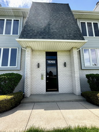 Front view of a two-story building with a distinctive sloped roof and multiple windows.