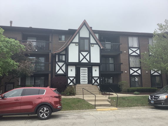 Front view of a three-story apartment building with a Tudor-style facade.