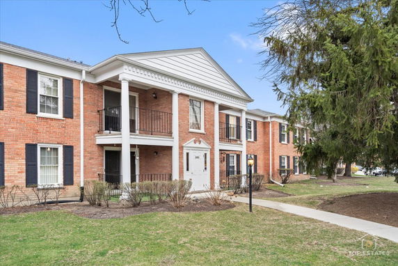 Front view of a two-story brick building with white columns and black shutters.