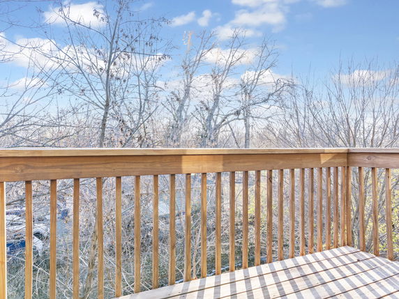 View from a wooden balcony with trees in the background.