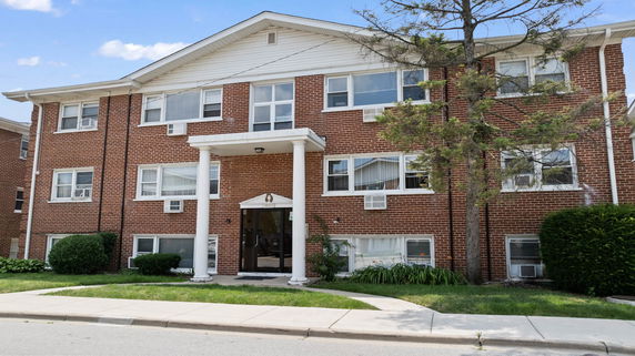 Front view of a two-story brick residential building with white columns at the entrance.