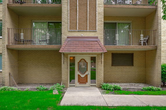 Front view of a multi-story brick building with balconies and an entrance door.