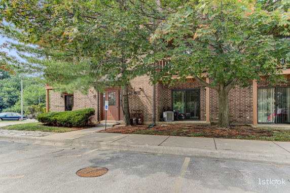 Front view of a brick building with a doorway and large windows.