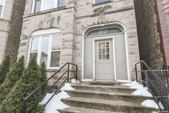 Front view of a stone-faced building entrance with stairs leading to a door.