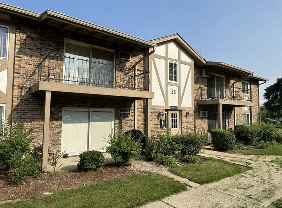 Front view of a two-story brick apartment building with balconies.