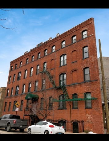 Front view of a multi-story brick building with fire escapes.