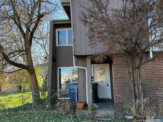 Front view of a multi-story house with brown siding and a small entrance.