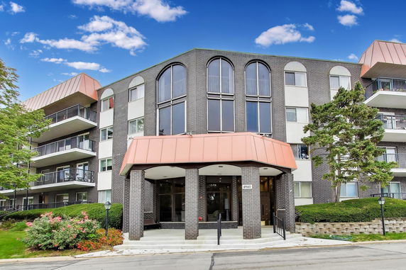 Front view of a multi-story apartment building with brick facade and large windows.
