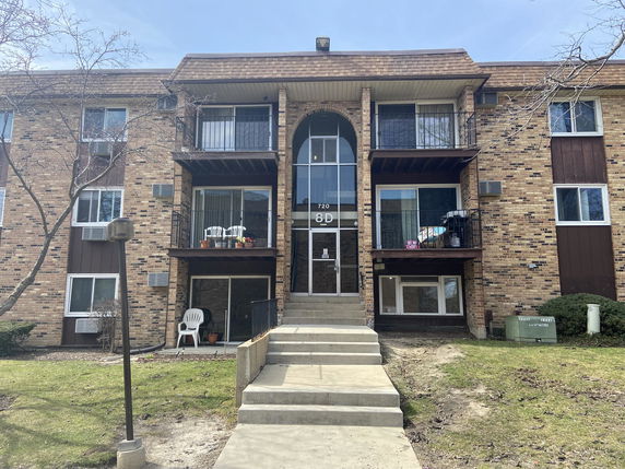 Front view of a three-story building with balconies and brick exterior.
