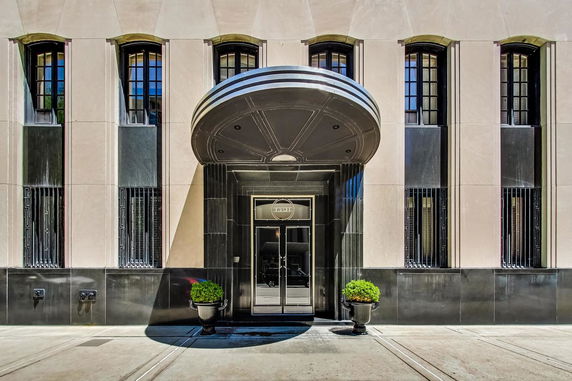 Front view of a building entrance with a large round canopy and decorative windows.