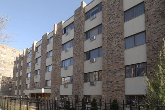 Front view of a multi-story apartment building with brick facade.