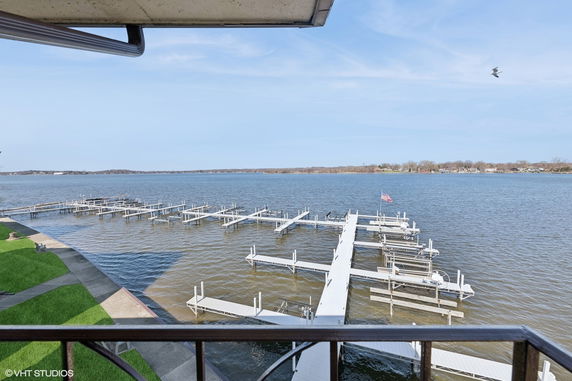 Panoramic view of a large body of water with boat docks extending into it, seen from a building balcony.