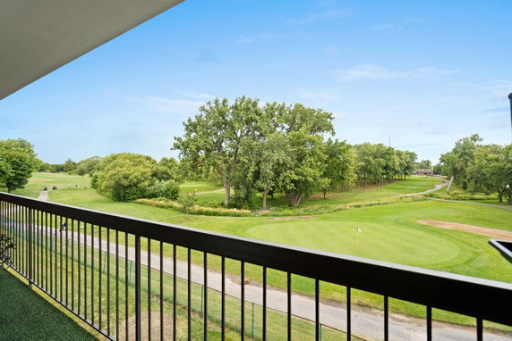Panoramic view from a building showing a golf course with trees and a green field.