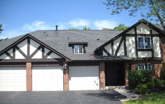 Front view of a house with a three-car garage and Tudor-style architecture.