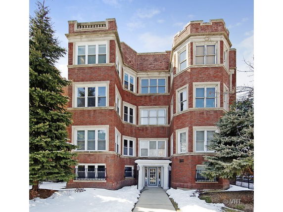 Front view of a multi-story brick apartment building with bay windows.