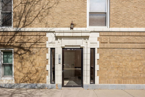 Front view of a brick building with a glass entrance door.