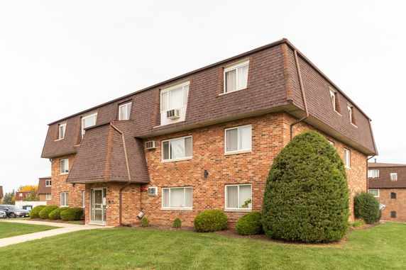 Front view of a multi-story brick apartment building with a shingle roof.