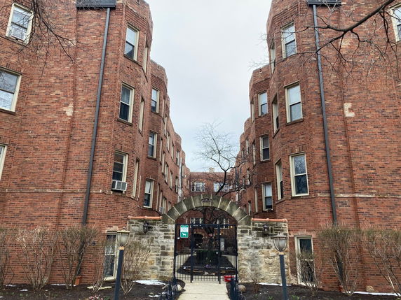 Front view of a multi-story brick building with an arched entrance.