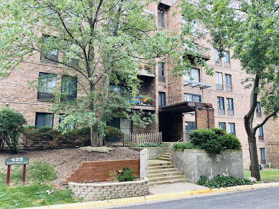Front view of a multi-story brick building with multiple windows and an entrance canopy.