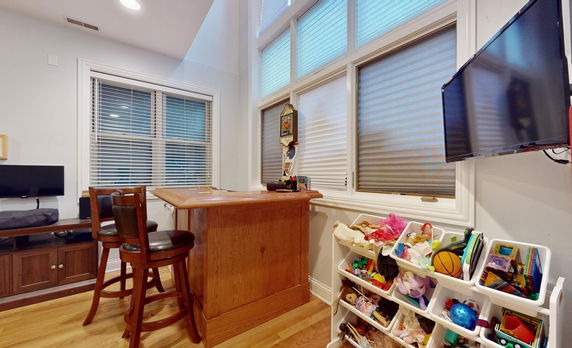 Room with a small bar, wooden stools, and toy storage bins filled with toys.