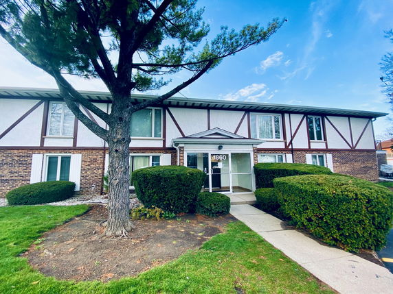 Front view of a two-story building with brick and wood paneling.