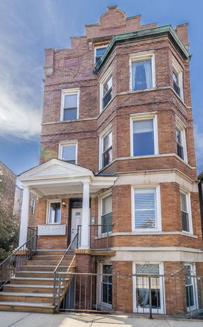 Front view of a multi-story brick building with a white columned entrance.