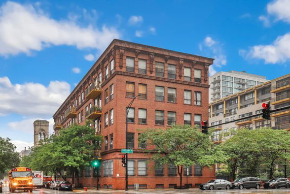 Front view of a multi-story brick building on a street corner.