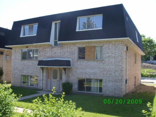 Front view of a two-story house with a dark roof and brick facade.