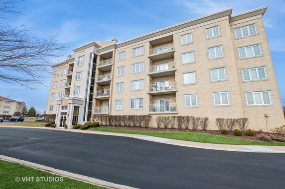 Front view of a multi-story apartment building with balconies and large windows.