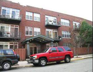 Front view of a multi-story brick apartment building with balconies.
