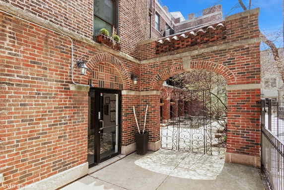 Front view of a brick apartment building entrance with an arched gateway.