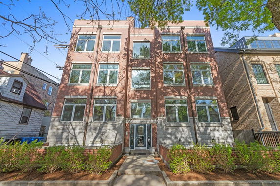 Front view of a multi-story brick building with large windows.