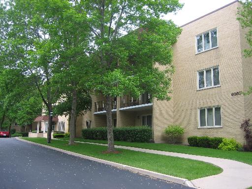 Front view of a multi-story brick apartment building with balconies.
