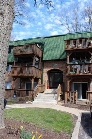 Front view of a multi-story building with balconies and a green roof.