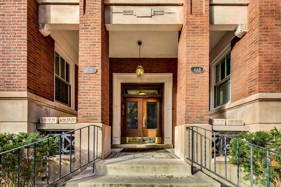 Front entrance of a brick building with a double door and decorative lighting.