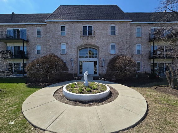 Front view of a multi-story brick building with entrance and balconies.