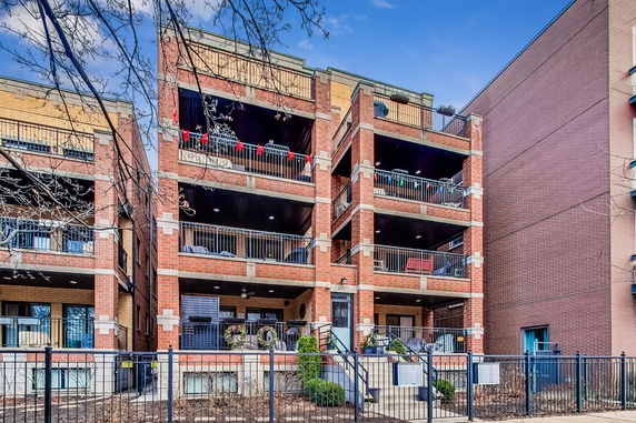 Front view of a multi-story brick apartment building with balconies.