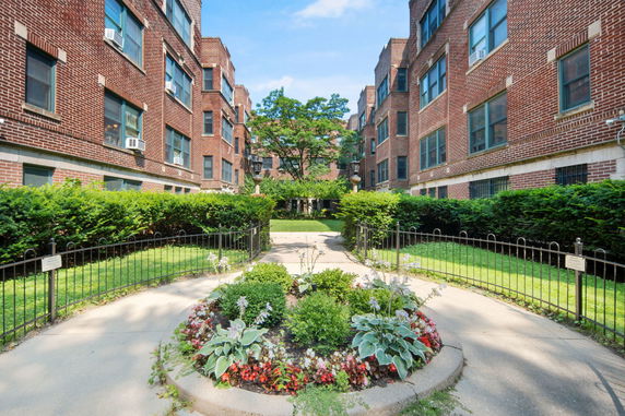 Front view of a brick apartment building with symmetrical design and multiple windows.