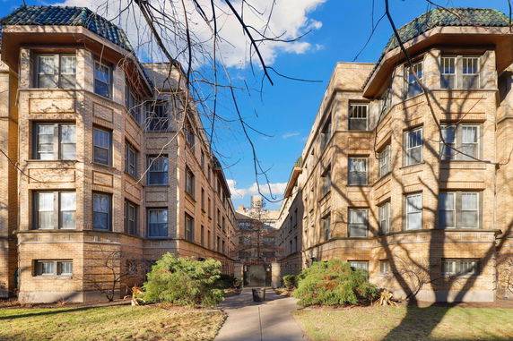 Front view of a multi-story brick apartment building with large windows and decorative roofline.
