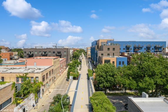 Panoramic view of urban buildings and a pathway surrounded by greenery.
