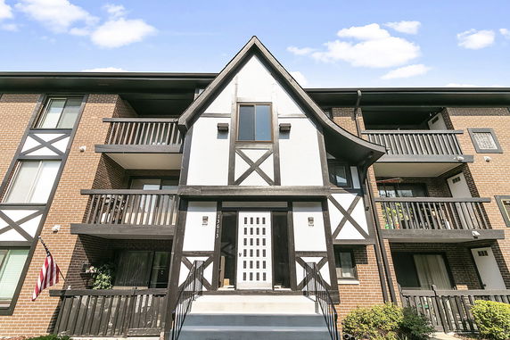 Front view of a multi-story building with brick and wood paneling.
